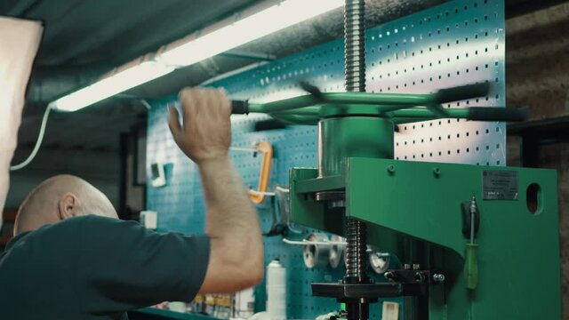 Car cardan shaft repair. A locksmith dismantles a faulty gimbal part using a mechanical press in a workshop. Close-up.