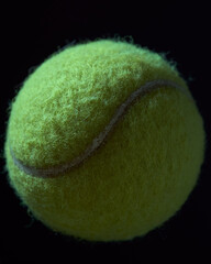 Green tennis ball on black background