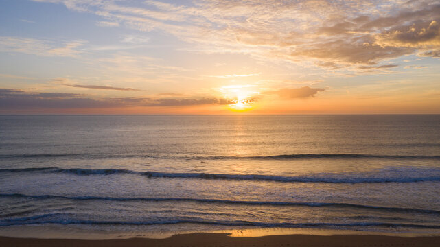 aerial view of the beach at sunset with beautiful clouds between the sun. views from above with drone to Zahora beach, Cadiz, Andalucia, Spain.