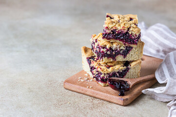 Shortcrust pie bars with berries jam and crumble on wooden board, light concrete background. Homemade bakery. Copy space.