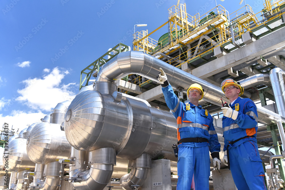 Wall mural teamwork: group of industrial workers in a refinery - oil processing equipment and machinery