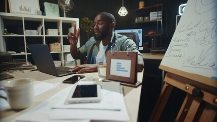 Positive african american businessman using computer at late night workplace.