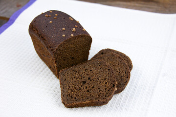 Homemade dark brown sourdough rye bread of Russian origin with coriander and caraway seeds on moneycomb towel backgroun.