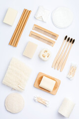 Creative layout, zero waste concept with natural biodegradable accessories. Bamboo toothbrushes, handmade packaging free soap shampoo bars, cotton buds pads, hygiene products luffa on white, top view