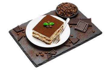 Traditional Italian Tiramisu square dessert portion on ceramic plate, pieces of chocolate bar and coffee beans on stone serving cutting board isolated on white
