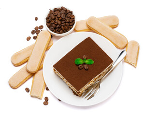 Traditional Italian Tiramisu square dessert portion on ceramic plate, savoiardi cookies and coffee beans isolated on white