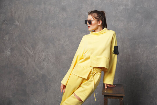 Young woman in yellow sportswear, pants and sweatshirt. Concept of fashionable sport outfit, indoors photo. Copy space.