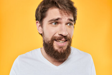 Obraz premium Man with emotional expression white t-shirt close-up studio yellow background