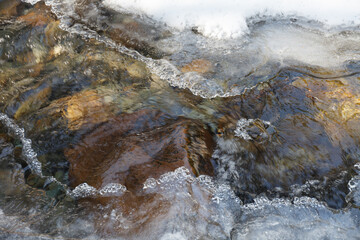 Warren falls - frozen creek under ice and snow with rocky shores. Sunny winter day
