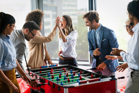Excited diverse employees enjoying funny activity at work break, creative friendly workers play game