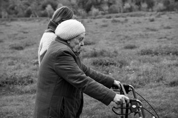 Elderly woman with walker taking a walk with granddaughter in winter