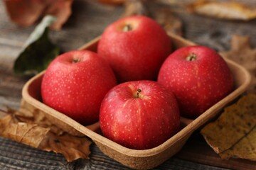Juicy red apples and autumn leaves on the table