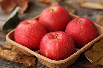 Juicy red apples and autumn leaves on the table