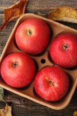 Juicy red apples and autumn leaves on the table