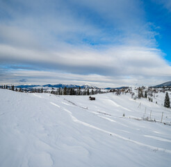 Countryside hills, groves and farmlands in winter remote alpine mountain village