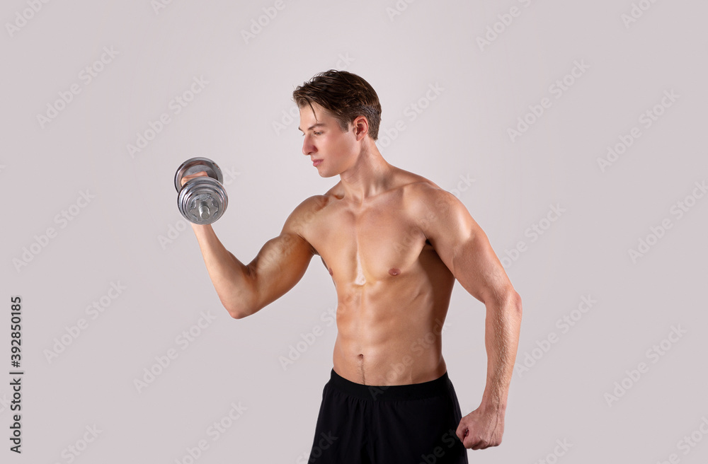 Wall mural bodybuilding strength workout. young muscular man exercising with dumbbells, pumping up muscles on l