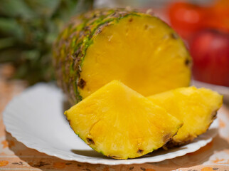 Pineapple fruit on white plate and red apples in the background