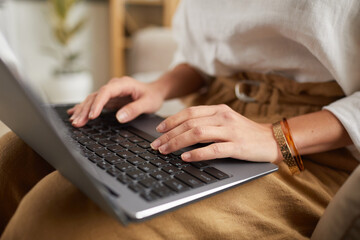 Close up of unrecognizable successful businesswoman typing on laptop keyboard while using internet and working from home, copy space
