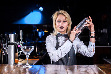 Girl barman formulates a cocktail on the pothouse