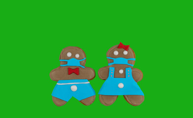 pair of gingerbread cookies on a green background. little men in medical masks.cookies made with your own hands. top view, copy space