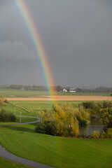 A rainbow visible very close over the green fields in southern Sweden after a summer rain