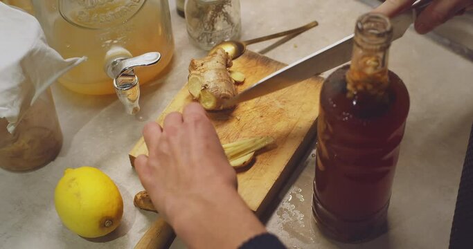 Healthy beverage kombucha.Female hands slicing fresh ginger in kitchen for fermented fresh drink.