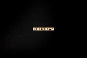 Wooden letters on a black background forming the word “lockdown”. Second wave during Coronavirus pandemic concept.