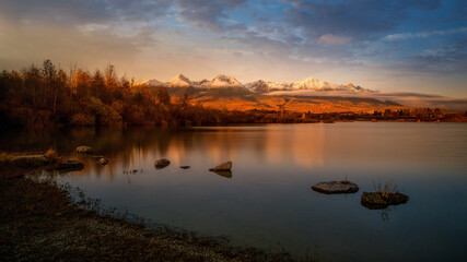 autumn pond with the reflection of the mountains on the surface at sunset