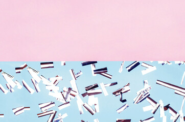 Silver confetti in the form of rectangles on a pink-blue background.