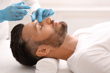 Fototapeta na wymiar Side view of bearded man getting beauty injection in salon