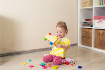 beautiful little child plays with wooden cubes. Kid playing on the floor in the children's room