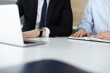 Unknown business people using laptop computer at the desk in modern office. Businessman or male entrepreneur is working with his colleague. Teamwork and partnership concept