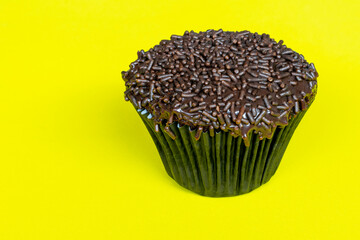 Chocolate cupcake with sprinkles, with yellow background