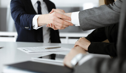 Unknown businessmen and woman sitting, working and discussing questions at meeting in modern office, close-up