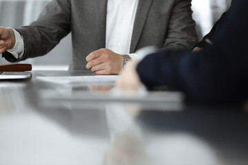 Unknown businessmen and woman sitting, working and discussing questions at meeting in modern office, close-up