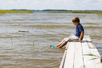little kid alone on a wooden lake pier