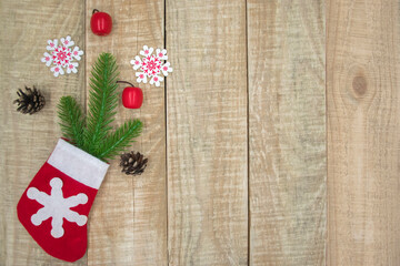 Christmas festive composition of Santa sock filled with gifts: spruce branches, snowflakes, fir cones and red small toys on wooden background. Christmas or New Year background with copy space.