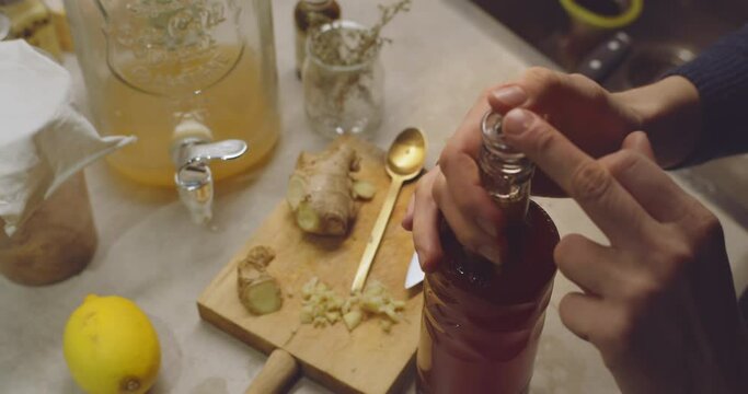 Healthy Kombucha fermented beverage homemade. Homemade lemon and ginger organic probiotic drink. Female closing the bottle of fresh drink.
