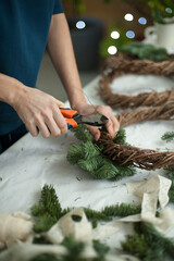 Woman doing Christmas fir wreath with natural materials. © Vasylyna Maksymovych