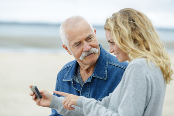 senior dad daughter checking mobile phone