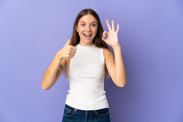 Young Lithuanian woman isolated on purple background showing ok sign and thumb up gesture