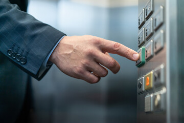 Businessman presses button with braille for blind. Close up shot of Caucasian male hand pressing key for closing doors in elevator of business center.  © Svyatoslav Lypynskyy