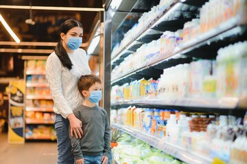 Mother and her son wearing protective face mask shop at a supermarket during the coronavirus epidemic