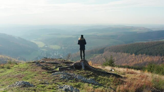 
a man is standing on a hill above a low mountain range filmed in 4k with movement

