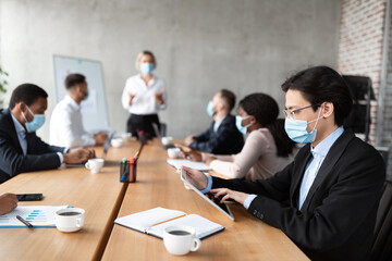 Asian Businessman In Mask Using Tablet During Corporate Meeting Indoor