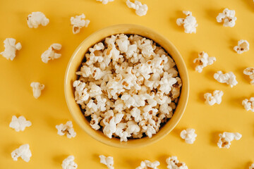 Fototapeta na wymiar Popcorn in a yellow bowl on a yellow background. Top view. Copy, empty space for text