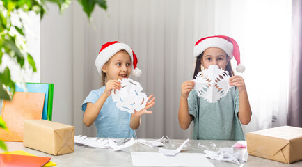 girls holding snowflakes from the paper at home indoor. The holiday, childhood, winter, celebration concept