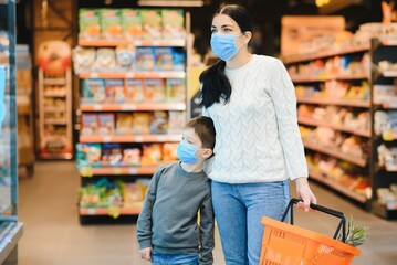 Shopping with kids during virus outbreak. Mother and child wearing surgical face mask buying fruit in supermarket. Mom and little boy buy fresh vegetable in grocery store. Family in shop.