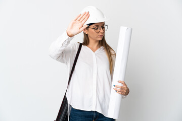 Young Lithuanian architect woman with helmet and holding blueprints isolated on white background making stop gesture and disappointed
