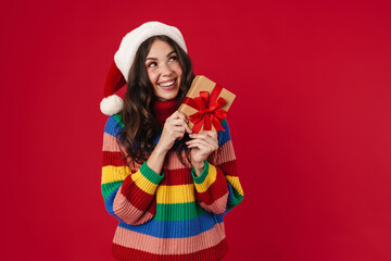 Beautiful happy girl in Santa Claus hat posing with Christmas gift
